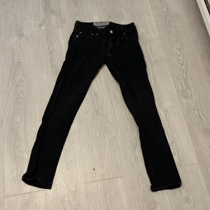 Svarta skinny jeans från Jacob Cohën - Snygga svarta jeans från Jacob Cohën med klassisk femficksdesign och diskret logga på bakfickan. Modellen är slim och skinny med smal passform och stretchigt jeanstyg som sitter tajt längs benen. Perfekta för en stilren och modern look. Passar bra till dig som gillar en lite mer slim outfit.