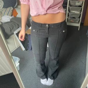 Svarta bootcut jeans  - Snygga svarta byxor med bootcut passform och dekorativa fickor framtill med knappar. Byxorna har låg midja och markerade sömmar längs benen. Perfekta för dig som gillar en klassisk men trendig look. Köpte på H&M när de var som mest eftertraktade, använda ungefär 10 gånger.
