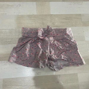 Blommiga shorts med rosett - Supersöta shorts med små rosa och lila blommor över hela tyget. 