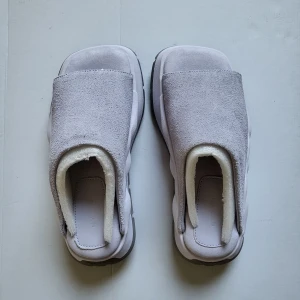Ljusgrå slip-on sneakers från Eytys/ Eytys Sensa Suede Iris - Unika slip-on sneakers från Eytys i ljusgrå mocka med chunky sula och fyrkantig tå. Skorna har en minimalistisk design utan snörning och en robust, mönstrad yttersula i grått. Perfekta för dig som gillar statement och modern stil.