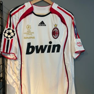 AC Milan Kaka Champions League tröja - Säljer en ikonisk AC Milan bortatröja från Adidas med Kaka och nummer 22 på ryggen. Tröjan är vit med röda och svarta detaljer, Champions League-märken på ärmarna och Bwin som sponsor. Klassisk passform i lätt och ventilerande material. Helt ny med tagg en replika 