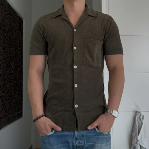 Grön kortärmad frotté skjorta A Day's March - Snygg grön kortärmad skjorta från A Day's March i mjuk frotté. Skjortan har klassisk krage, vita knappar framtill och en bröstficka. Perfekt för en avslappnad och stilren look. Nypris 900.