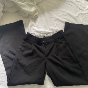 Svarta kostymbyxor från Gina Tricot XS - Snygga svarta kostymbyxor från Gina Tricot i storlek XS. Byxorna har raka ben, hällor för bälte och klassisk stängning fram. Perfekta för en clean och stilren look. Materialet känns mjukt och följsamt.Säljer pga den inte kommer till användning🫰🏻