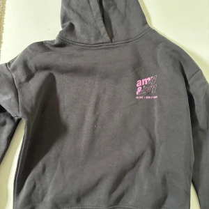 Mörkgrå hoodie med tryck - Säljer en mörkgrå hoodie från Amy & Ivy med tryck i rosa och lila. Framsidan har en liten logga och text, medan baksidan har stort tryck som är så coolt