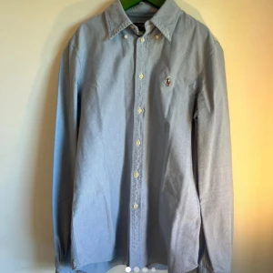 Blå skjorta från Polo Ralph Lauren S - Klassisk ljusblå skjorta från Polo Ralph Lauren i bomull. Den är i super skick, inga defekter, nypris 1800 kr mitt = 249 kr, skriv om minsta lilla fundering!