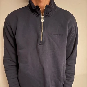 Mörkblå half zip tröja J.Lindeberg - Säljer en stilren mörkblå tröja från J.Lindeberg med hög krage och half zip-dragkedja. Tröjan är i mjuk bomull och har diskret broderad logga på bröstet. Perfekt för lager-på-lager och chill vardagsstil.