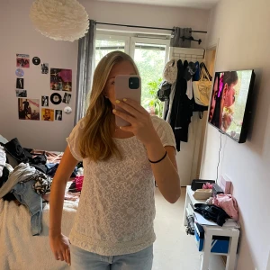 Vit broderad blus från Odd Molly - Supersöt vit blus från Odd Molly med broderade detaljer och korta ärmar. Blusen har rund halsringning, spetskant nertill och ett diskret mönster över hela tyget. Perfekt till jeans eller kjol för en fräsch look.