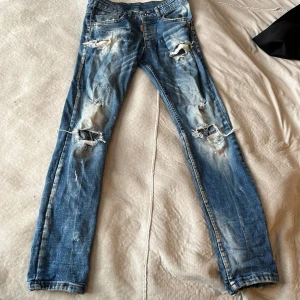 Blå slitna jeans från Dsquared2 - Riktigt snygga blå jeans från Dsquared2 med rejält slitna detaljer och trasiga partier på benen. Klassisk femficksmodell med röd Dsquared2-label bak. Jeansen har en smal passform och cool tvätt för en edgy streetstil.