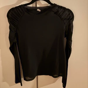 Svart långärmad med lite puff och lite genomskinliga armar - Bra skick, en liten defekt som man ser på första bilden men ganska säker på att den går bort i tvätten!