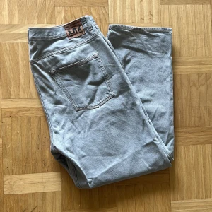 Gråa Sweet SKTBS jeans - Snygga grå jeansbyxor från Sweet SKTBS i storlek XL. Klassisk femficksmodell med raka ben och orangea sömmar. Byxorna har normal passform och är tillverkade i slitstarkt bomullsmaterial. Perfekt för dig som gillar streetwear och vill ha en clean look. köpt för ca 1 år sedan från Junkyard. Sparsamt använda i fint skick Mått : Längd (från midja - ankel) 114cm, Midje bredd - 53cm, Mått ben längd: ca 80cm, Mått ben bredd: Ca 30cm