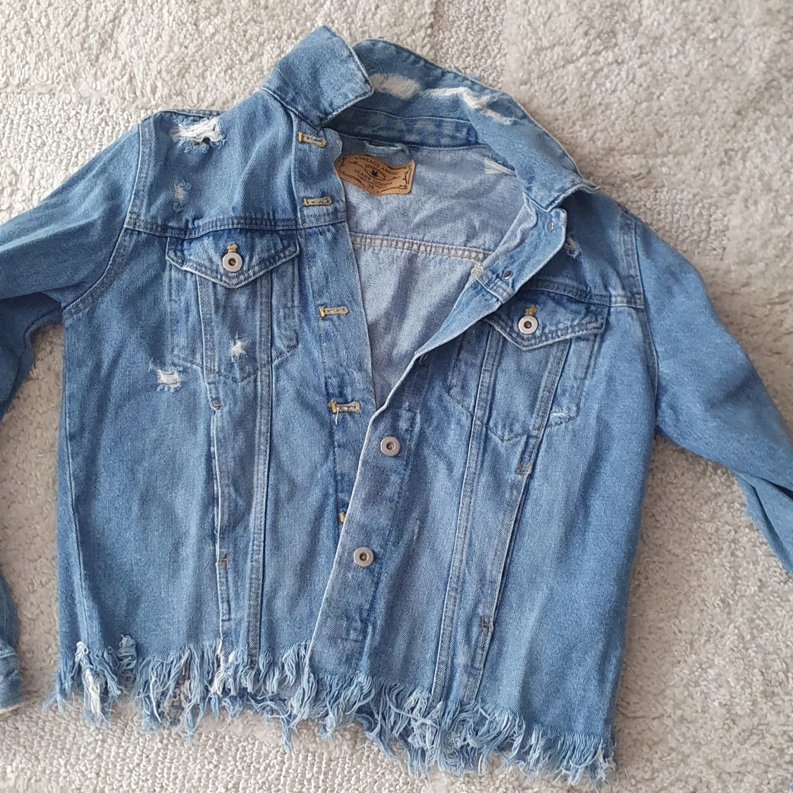 Blå jeansjacka med slitningar
