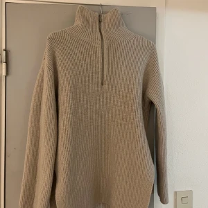 Beige stickad half zip-tröja H&M - Säljer en beige stickad tröja från H&M med hög krage och half zip-dragkedja. Tröjan är ribbstickad, har lång ärm och en loose fit. Nyskick! Hör av dig om du har funderingar😊