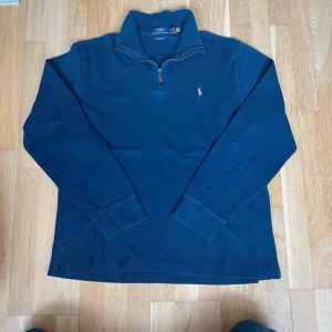 Ralph Lauren Quarter/Half Zip - Säljer en marinblå långärmad tröja från Polo Ralph Lauren med klassisk krage och half zip-dragkedja. Tröjan har broderad logga på bröstet och är gjord i mjuk bomull. Perfekt för dig som gillar stilren och tidlös design. Hör av er vid frågor!