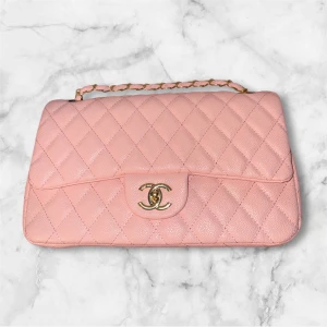 Rosa quiltad Chanel handväska i skinn - Superfin rosa handväska från Chanel i quiltat skinn med klassisk guldfärgad kedja och ikoniskt CC-spänne framtill. Insidan är vinröd och har präglad Chanel-logga. Perfekt för dig som vill ha en lyxig och tidlös accessoar med trendig vibe.