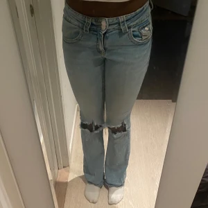 Utsvängda blåa jeans med hål i knäna och lång midja  - Utsvängda blåa jeans med hål i knäna 