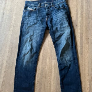 Blå jeans från Diesel Industry - Snygga blå jeans från Diesel Industry med klassisk femficksdesign och coola slitningar. Jeansen har raka ben och orangea kontrastsömmar. Perfekta för dig som gillar en avslappnad men ändå stilren look.