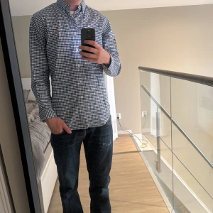 Rutig blåvit skjorta från Polo Ralph Lauren - Säljer en klassisk rutig skjorta från Polo Ralph Lauren i blått och vitt. Skjortan har lång ärm, knappar hela vägen och orange broderad logga på bröstet. Tillverkad i mjuk bomull och har en normal passform med button-down krage. Storlek L men passar även M. Jag är 185 och väger 75kg