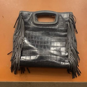 Svart Maje väska  - Fin svart Maje väska med fransar. Den har slitage på handtagen som har gjort att märket har skavts av och ena handtaget har gått upp. Den är köpt här på Plick innan, därför kan den vara lite extra sliten pga att den är begagnad❤️