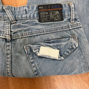 Ljusblå baggy jeans från PXJ - Säljer ett par ljusblå jeans från PXJ med baggy passform och raka ben. Jeansen har coola detaljer som unik bakficka med vit patch och klassisk femficksdesign. 