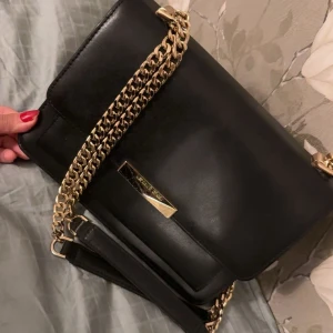 Svart axelväska Michael Kors skinn - Snygg svart axelväska från Michael Kors i slätt skinn med guldfärgade kedjor och detaljer. Säljer för  1500kr men priset kan diskuteras 🤍