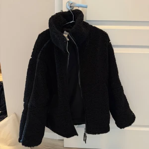 Svart teddyjacka / pilejacka - Mysig svart teddyjacka/pilejacka med hög krage . Jackan har en oversized passform och är tillverkad i fluffigt teddy-material.