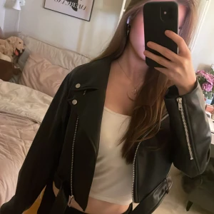 Svart skinnjacka från Monki - Säljer en svart skinnjacka från Monki i bikerstil. Jackan har silvriga dragkedjor, Helt oanvänd och har hängt i garderoben sen dess!💗Är i storlek XXS.