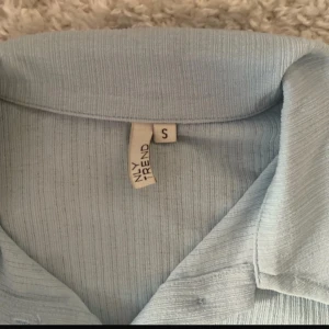 Ljusblå ribbad skjorta från NLY Trend - Säljer en ljusblå ribbad skjorta från NLY Trend i storlek S. Skjortan har långa ärmar, klassisk krage och knäppning framtill. Perfekt för dig som gillar en enkel men snygg stil.