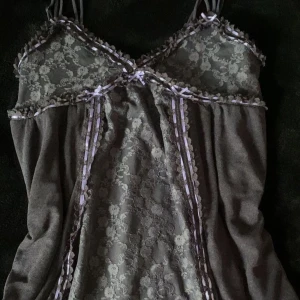 Söt babydoll klänning - Jätte söt grå och lila  klänning med spets och rosetter. Endast använd en gång. Köpt på Urban outfitters för något år sedan för ungefär 600kr men har inte kommit till användning 