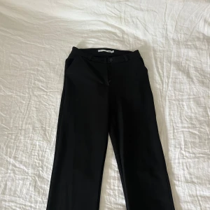 Svarta kostymbyxor från 157 - Säljer ett par klassiska svarta kostymbyxor från 157 i storlek XS. Byxorna har normal passform, raka ben och stängs med knapp och dragkedja. Perfekta till många olika outfits.