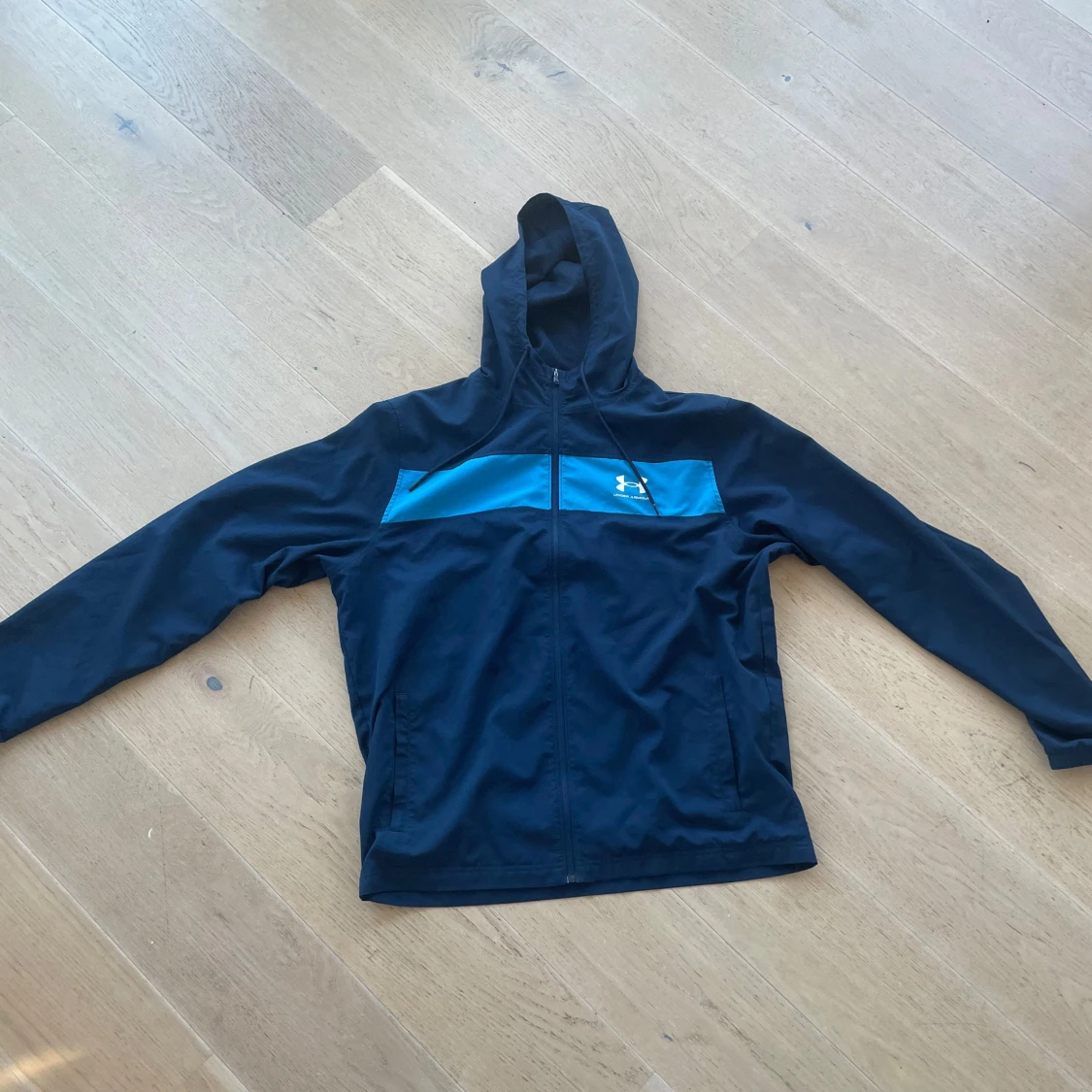 Svart träningsjacka med blå detalj från Under Armour