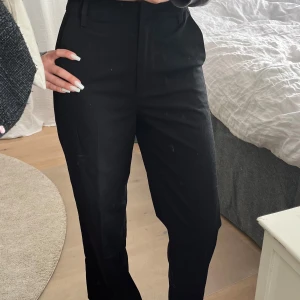 Svarta kostymbyxor från Bik Bok - Säljer ett par svarta kostymbyxor från Bik Bok med hög midja och raka ben. Byxorna har hällor för bälte och diskreta fickor framtill. Perfekta för en stilren och klassisk look.
