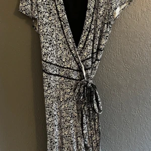 Blommig omlottklänning från BikBok - Säljer en svartvit blommig omlottklänning från BikBok med knyt i midjan och v-ringning. Klänningen har korta ärmar och ett fint blommönster över hela tyget. Perfekt för dig som gillar en feminin och avslappnad stil.