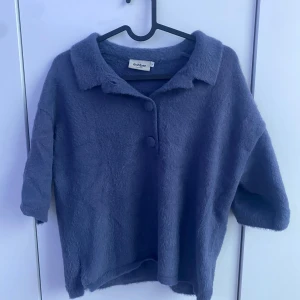 Lila fluffig kofta från Dobber - Supermjuk och fluffig lila kofta från Dobber med krage och två stora knappar framtill. Koftan har trekvartsärm och en avslappnad passform, perfekt för lager-på-lager under kyliga dagar men ändå få ett snygg look.