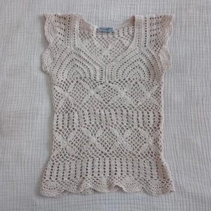 Beige virkad topp - Säljer en beige virkad topp med korta ärmar. Toppen har ett detaljerat spetsmönster och vågig nederkant. Perfekt för en bohemisk. Den är mer beige i verkligheten än på bilden! 