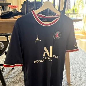 PSG matchtröja från Jordan x Nike - Mörkblå Paris Saint-Germain fotbollströja med vita och röda detaljer på krage och ärmslut. PSG-logga på bröstet, Jordan-logga och sponsortryck framtill. Klassisk rund hals och sportig design. Köpt på xxl storlek L, säljes då jag inte använder längre