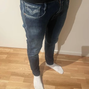 Mörkblå jeans från Replay - mörkblå  Replay Anbass jeans med en klassisk femficksdesign. De har en slim passform och är tillverkade i ett stretchigt denimtyg för extra komfort. Perfekta för en stilren look. En defekt på sista bilden. W29 L32
