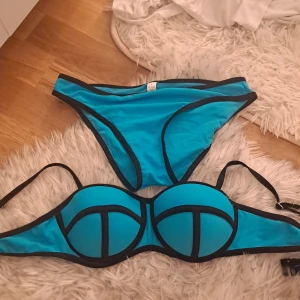 Turkos bikini med svarta kanter - Säljer en turkos bikini med svarta kontrastkanter. Överdelen har bygel och justerbara axelband, och underdelen är klassisk trosa. Materialet är 82% polyamid och 18% elastan. Perfekt för stranden eller poolen!