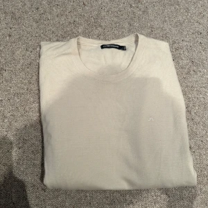 Beige stickad tröja från J.Lindeberg - Snygg beige stickad tröja från J.Lindeberg med rund halsringning och diskret broderad logga på bröstet. Perfekt för en stilren och enkel look. Passar bra till både jeans och chinos. Använd 2 gånger tvättad en gång så den är som ny. Nypris 1600kr mitt pris 600kr 