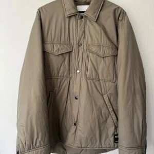 Jacka i Gore-Tex, Samsøe Samsøe L - Jacka från Samsøe Samsøe. Den  är gjord i  GORE-TEX Infinium-material som både skyddar mot regn och blåst men samtidigt andas och är svalt mot kroppen.