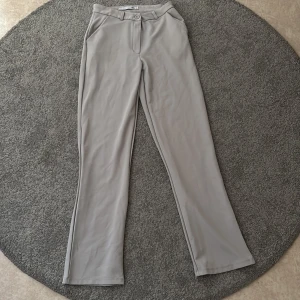 Grå/beigea kostymbyxor  - Säljer ett par stilrena grå kostymbyxor från 157 i storlek XS. Byxorna har normal passform, raka ben och låg i midjan. Perfekta för en clean och enkel look. Aldrig använda då dom är för långa på mig. Tråden vid fickorna är lite slarvigt sydda och har gått upp lite, men inget som påverkar skicket eller som syns när man har på sig dom.🌸🌸