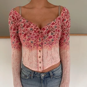 Blommig croppad kofta med knappar - Superfin croppad kofta i rosa och rött med blommigt mönster och v-ringning. Väldigt skönt, mjukt och gsndka tnut material så den funkar som en vanlig topp också! Passar xs men nog s också!
