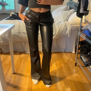 Svarta bootcut skinnbyxor från Bershka - Säljer ett par svarta skinnbyxor från Bershka i storlek S. Byxorna har låg midja, bootcut. Aldrig använda.