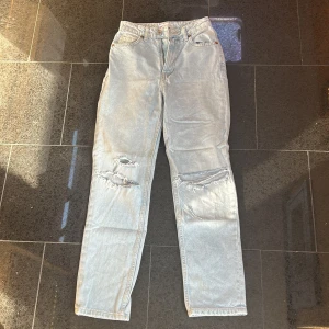 Ljusblå slitna jeans från Zara - Säljer ett par ljusblå jeans från Zara med raka ben och slitningar vid knäna. Jeansen har klassisk femficksdesign och normal passform. Perfekta för en avslappnad stil.