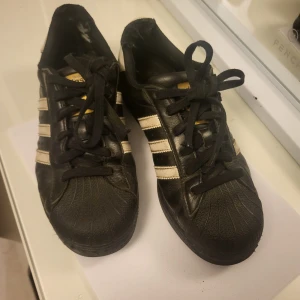 Adidas Superstars - Svarta skor från adidas, ganska slitna som man kan se på bild 3 och 4 men de funkar fortfarande. 