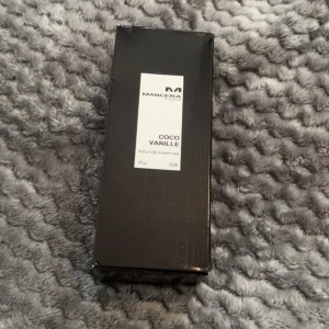 Mancera Coco Vanille Eau de Parfum 120 ml - Helt ny Mancera Coco Vanille är en lyxig parfym i en elegant, genomskinlig glasflaska med silverfärgad kork. Doften har tydliga inslag av kokos och vanilj, vilket ger en varm och exotisk känsla. Flaskan rymmer 120 ml och har en stilren vit etikett med svart text.