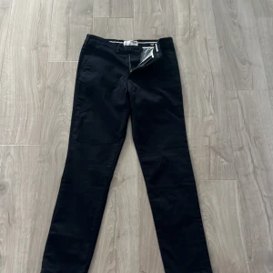 Svarta chinos med normal passform - Säljer ett par marin blåa chinos med klassisk rak passform. Byxorna har dragkedja och knäppning fram samt fickor både fram och bak. Perfekta till både vardagslooken och mer uppklädda tillfällen.