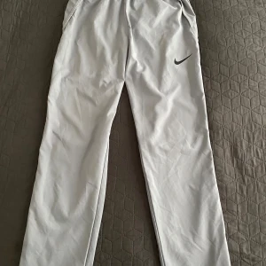 Nike drifit byxor - Snygga grå träningsbyxor från Nike med svart logga på låret. Byxorna har en rak passform och är tillverkade i ett lätt syntetmaterial som passar perfekt för träning eller sport. Storlek M men passar S perfekt också. Priset KAN diskuteras vid snabbaffär.