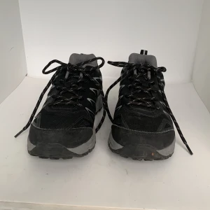 Svarta sneakers med grå detaljer - Svarta sneakers från Trekmates med grå och vita detaljer. Skorna har snörning, mesh- och syntetmaterial samt en robust, mönstrad sula för extra grepp. Perfekta för vardagsbruk eller lättare träning.