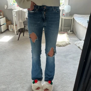 Blå jeans med hål på knäna - Säljer ett par blå bootcut lågmidjade jeans! Säljer pga att jag de ör för korta, är 172 cm🩵