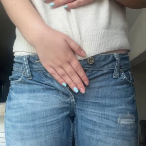 Low rise ljusblå jeans med detaljer - Säljer ett par low rise blå jeans från Roxy med slitningar och dekorativa stenar. Jeansen är nästan aldrig använda då de är för små för mig, de är raka i passformen. Öppen för bud! Bara att fråga om fler bilder!                                               Midjemått rakt över=34 cm                                          Benbredd där nere rakt över=16 cm                              Innerbenslängd=83 cm.                                                  Midjehöjd=16 cm